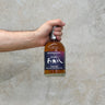 A hand holding a bottle of Eigashima Akashi Peated Malt 5 Year Old PX Cask Whisky with a concrete background.