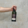 A hand holding a bottle of Ardbeg Spectacular Whisky with a concrete wall in the background.
