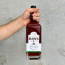 Hand holding a bottle of Bain's 18-year-old whiskey against a gray background
