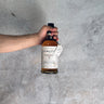 Hand holding a bottle of Balvenie whisky aged 25 Years against a gray concrete background