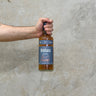 A hand holding a bottle of Benriach 21 Year Old whisky with a concrete background.