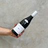 A hand holding a bottle of Vignoble Berthier 2020 Sancerre Red wine against a concrete background.