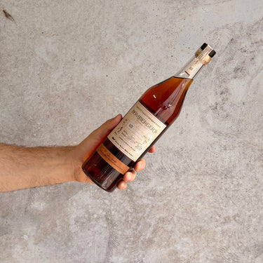 Hand holding a bottle of Bomberger's Small Batch Whiskey against a concrete background
