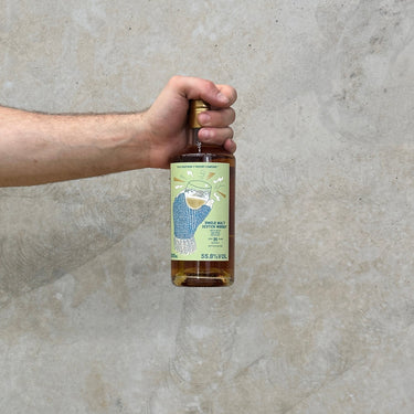 A hand holding a bottle of Ben Nevis 25 Year Old whisky with a label showing the distillery and the text 'That Boutique-y Whisky Company'.