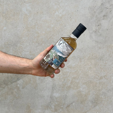 A hand holding a bottle of Inchgower 17 Year Old whisky with a label that includes the distillery name and the age.