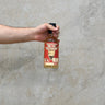 A hand holding a bottle of Jura 20 Year Old - Batch 4, That Boutique-y Whisky Company against a grey concrete background.