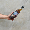 A hand holding a bottle of Bunnahabhain 11 Year Old Sherry Cask Whisky with a label depicting a stained glass window.