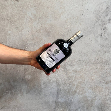 Hand holding a bottle of Bunnahabhain whisky bottle against a gray concrete background