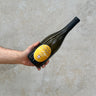 A hand holding a bottle of Les Rocailles 2020 Chignin-Bergeron AOC Rousanne wine with a yellow label.