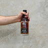 A hand holding a bottle of Ardbeg Darkness 12 Year Old Oloroso Cask single malt Scotch whisky against a grey background.