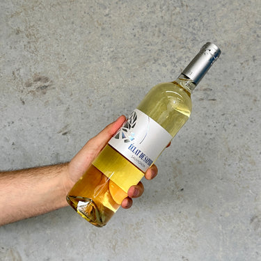 Hand holding a bottle of Sauvignon White wine with a label against a gray background