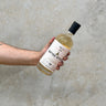 A bottle of Caol Ila Jean Boyer Gifted Stills Of Scotland 2016 Whisky held in a hand against a grey textured background.