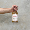 Hand holding a bottle of Glenfarclas whisky against a concrete wall.