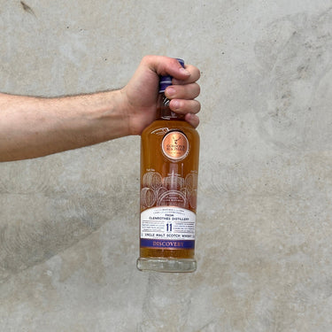 A hand holding a bottle of Gordon & Macphail Discovery Glenrothes 11 Year Old Sherry Cask Whisky.