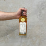 A hand holding a bottle of Gordon & Macphail Connoisseurs Choice Benriach 1999 Whisky against a grey background.