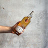 Hand holding a bottle of whiskey against a gray concrete background