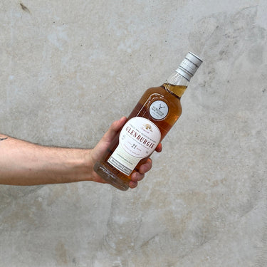 A hand holding a bottle of Glenburgie 21 Year Old whisky with a label that includes the distillery name and the age.