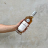 Hand holding a bottle of Gordon & Macphail Linkwood whisky against a concrete wall.