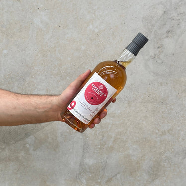 A hand holding a bottle of Craigellachie Hunter laing Hepburn's Choice 9 Year Old Whisky with a concrete background.