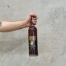 A hand holding a bottle of High West Campfire Barrel Select Oloroso Cask Whisky with a concrete background.
