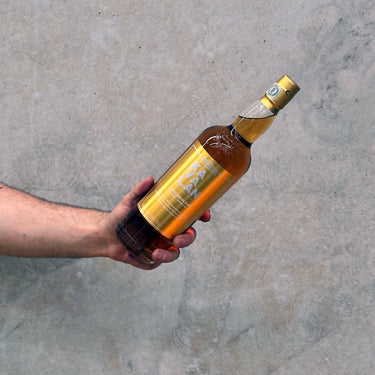 Hand holding a bottle Kavalan Ex-Bourbon Oak Taiwanese whisky against a concrete background