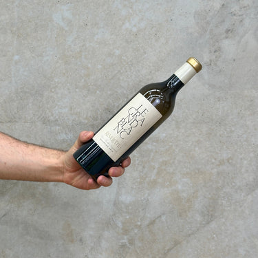 A hand holding a bottle of Chateau Revellette 2018 Le Grand Blanc wine