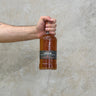 A hand holding a bottle of Ledaig 9 Year Old Bordeaux Cask Whisky with a concrete background.