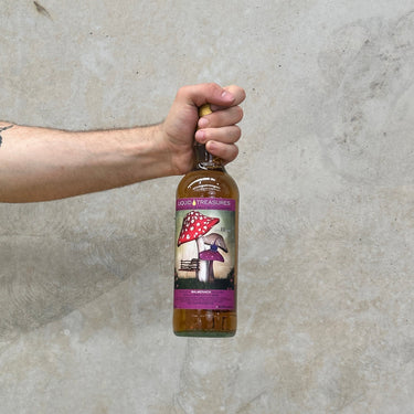 Hand holding a bottle of liquid treasures Balmenach whisky against a concrete wall.