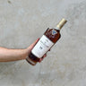 A hand holding a bottle of Macallan 18 Year Old Double Cask Whisky with a label that includes the brand name and the age statement.