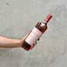 A hand holding a bottle of Macallan The Harmony Collection - Rich Cacao Whisky against a grey background.