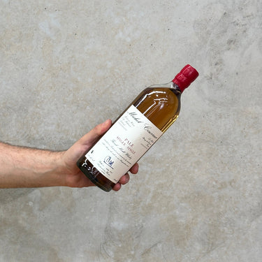 A hand holding a bottle of Michel Couvreur Pale Single Malt Whisky with a label that includes the brand name and the type of whisky.