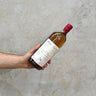 A hand holding a bottle of Michel Couvreur Pale Single Malt Whisky with a label that includes the brand name and the type of whisky.