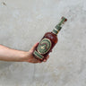 A hand holding a bottle of Michter's Limited Edition Barrel Strength Rye Whisky with a concrete surface in the background.