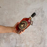 Hand holding a bottle of Michter's bourbon against a neutral background