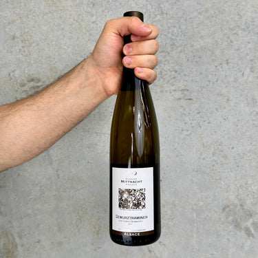 Hand holding a wine bottle with a label against a gray background