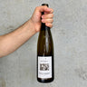 Hand holding a wine bottle with a label against a gray background