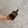 Hand holding a bottle of Ounce Single Malt Whisky against a concrete background