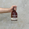 A hand holding a bottle of Overeem Port Cask - Cask Strength Whisky with a clear label on the bottle.