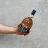 A hand holding a bottle of Overeem Sherry Cask Distillers Strength Whisky with a concrete background.