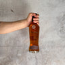 Hand holding a bottle of Pokeno Whisky Single Cask - Port Cask against a gray concrete background