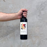A hand holding a bottle of Château Revelette 2019 Château Red wine against a concrete background.