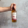 Hand holding a bottle of Roseisle Single Malt Scotch Aged 12 Yrs against a gray concrete background