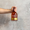Hand holding a bottle of Overeem whisky against a gray background
