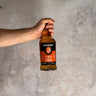 Hand holding a Springbank whisky bottle against a gray concrete background