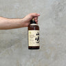 Hand holding a bottle of Vintage Suntory Pure Malt Whisky 1984 against a gray background