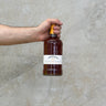 A hand holding a bottle of Tobermory 23 Year Old Oloroso Cask Whisky with a concrete background.