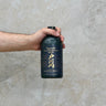 A hand holding a bottle of Togouchi 15 Year Old Whisky with a concrete background.