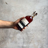 Hand holding a bottle of Waubs Harbour whiskey against a gray concrete background