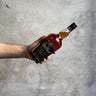 Hand holding a bottle of Weller 12 Year Old bourbon against a concrete background