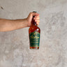 Hand holding a bottle of Weller Special Reserve whiskey against a textured gray background